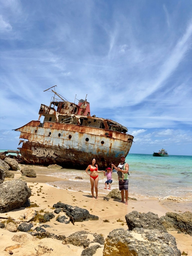 Family standing barefoot in front of turquoise waves in Anguilla