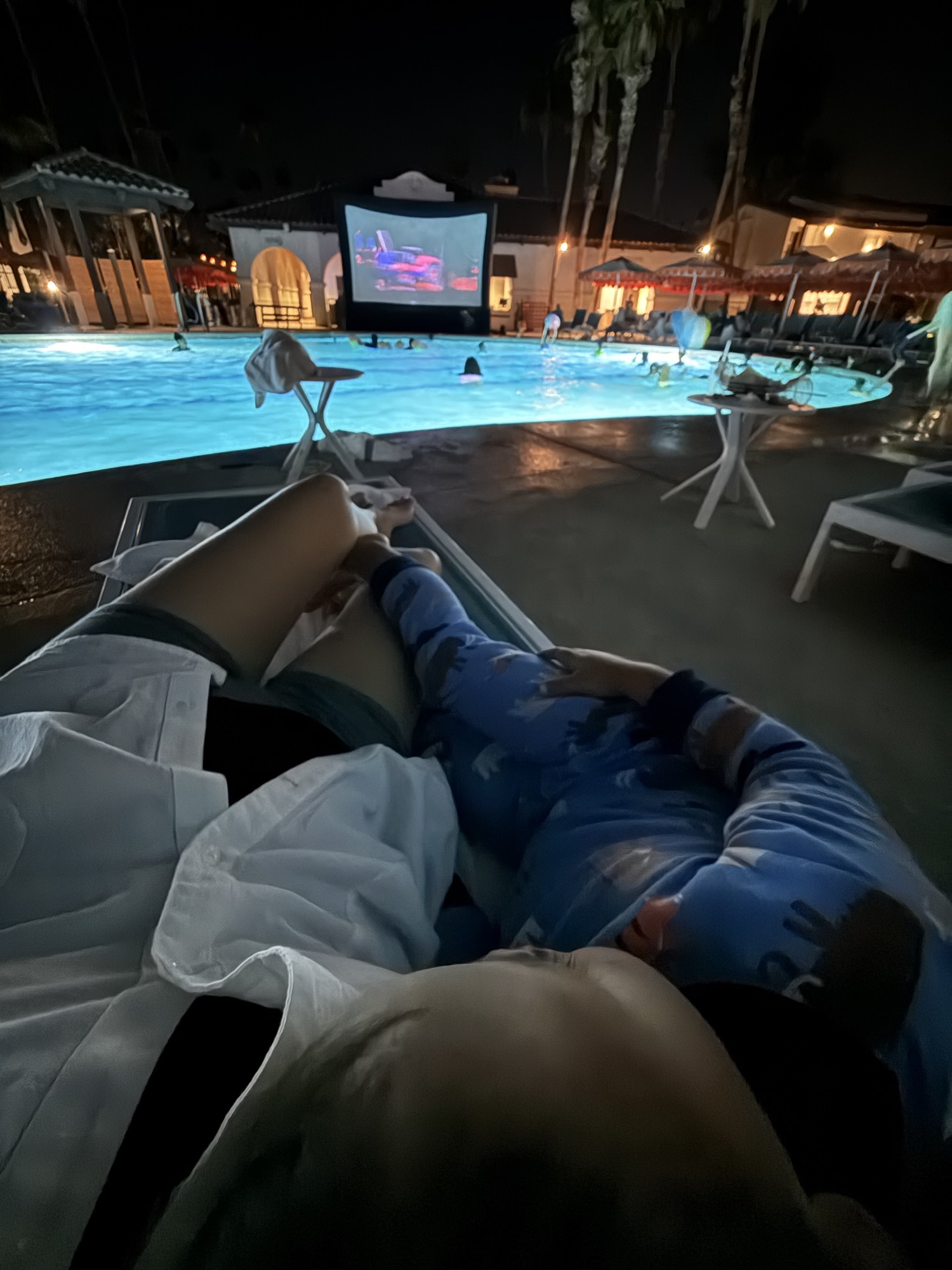 Toddler in pajamas cuddled up at poolside movie night