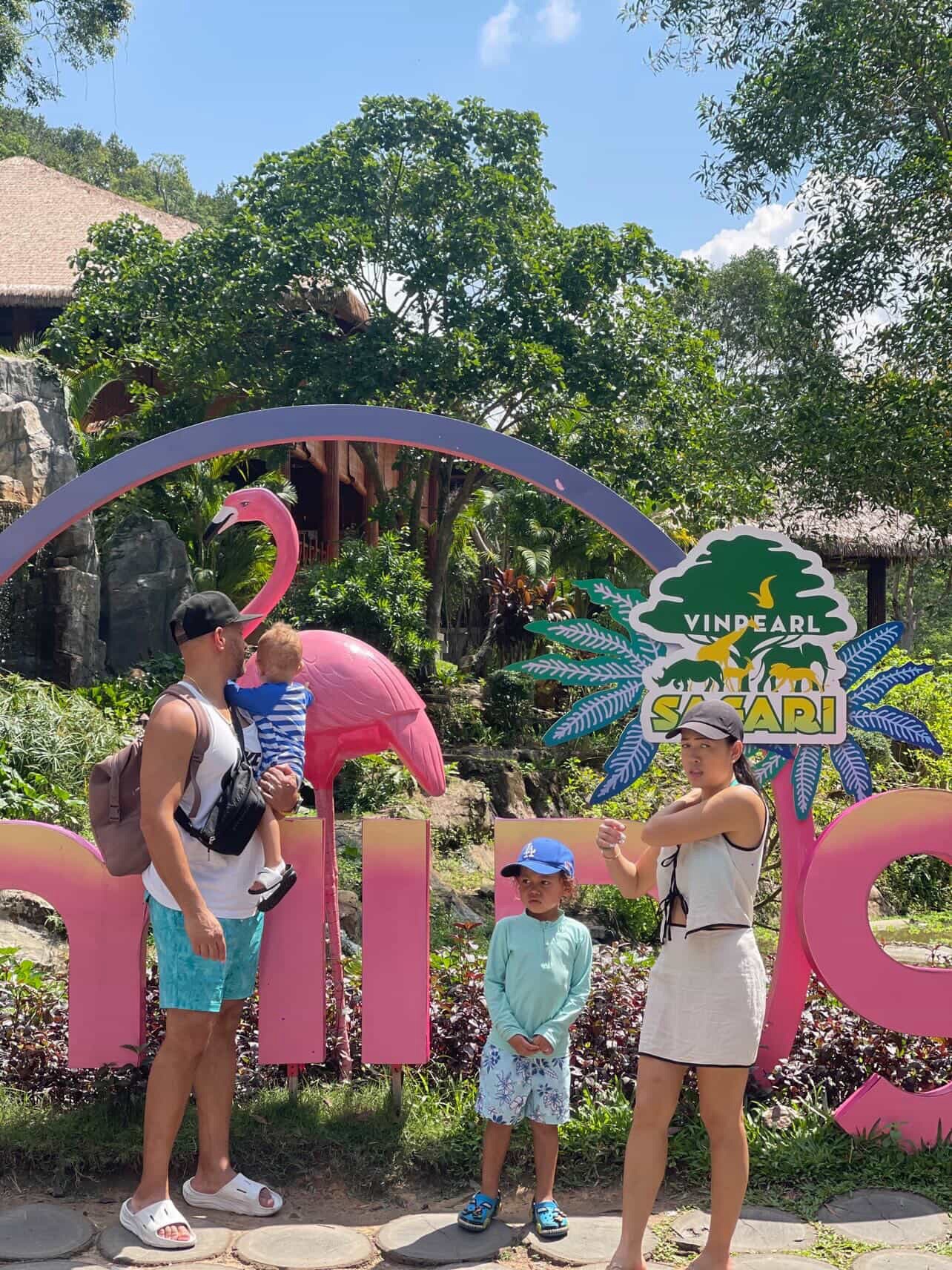 Family visiting Vinpearl Safari in Vietnam with kids standing at the colorful entrance sign