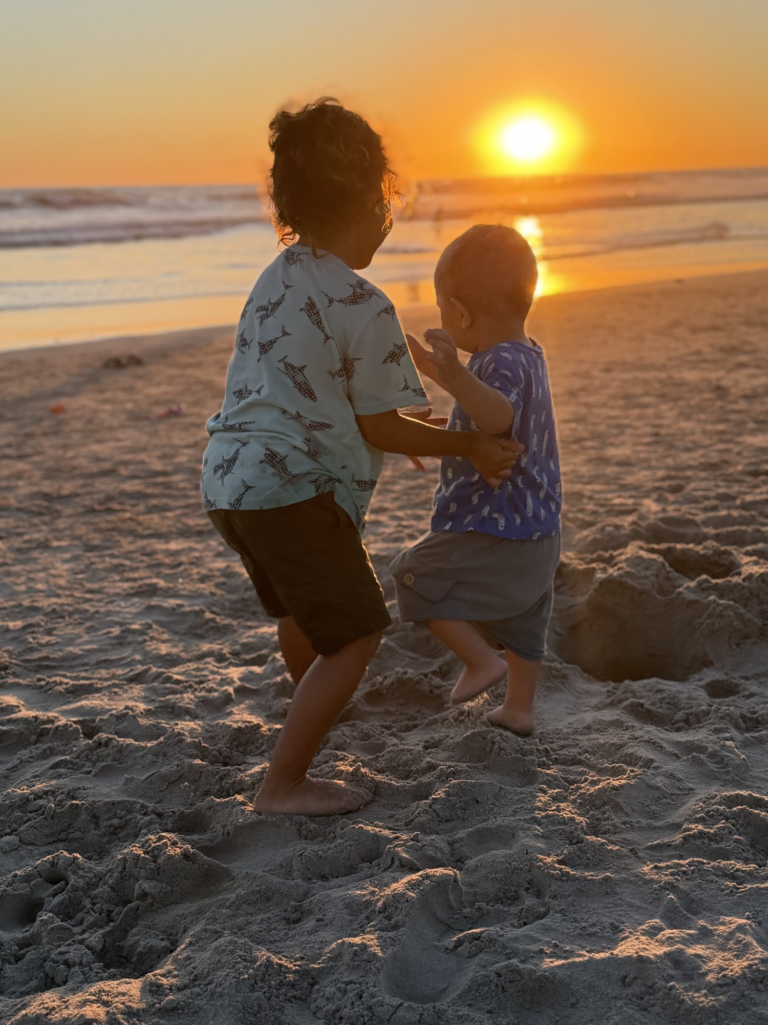 Two kids playing in the sand at sunset in Oceanside