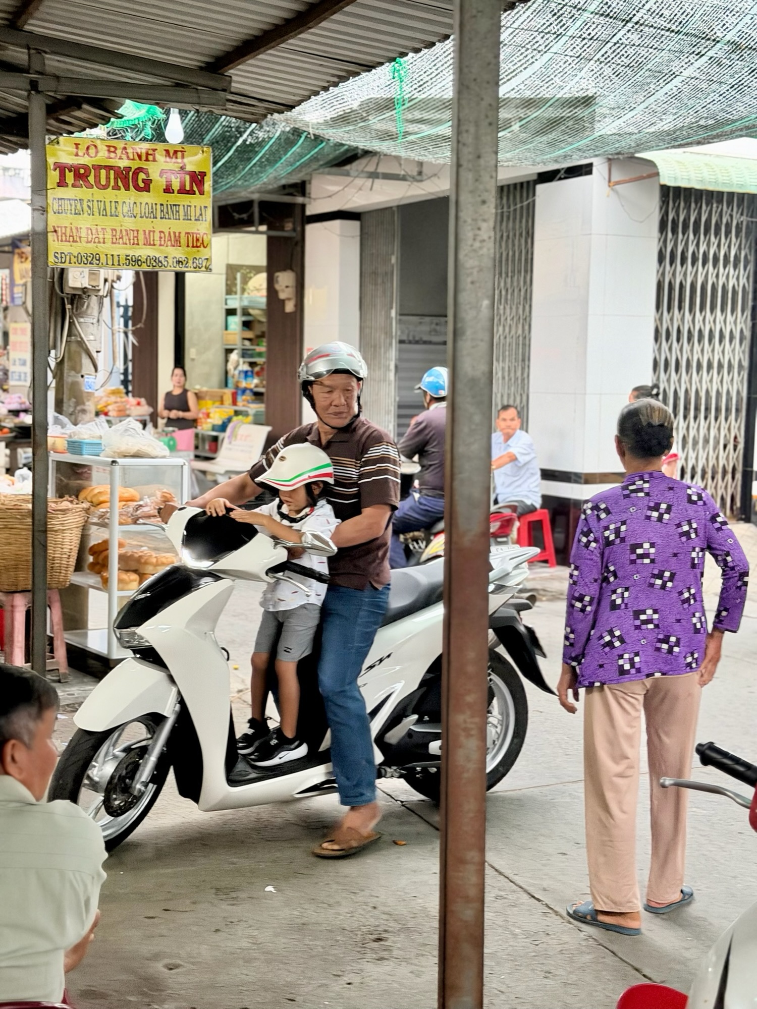 Child riding on a moped with Vietnamese relative on a busy street during a Vietnam family trip