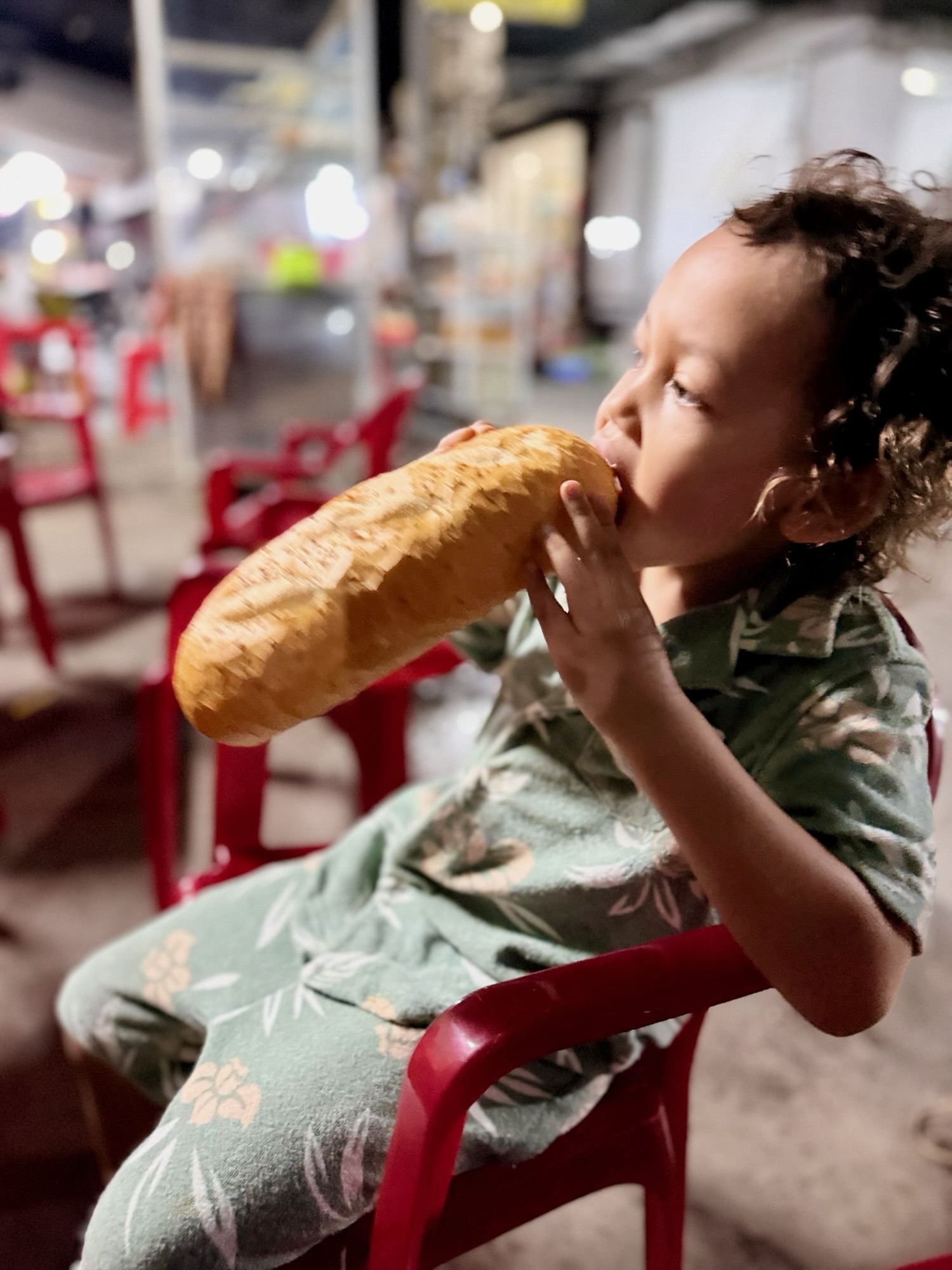 Child enjoying a large banh mi sandwich during a Vietnam family trip
